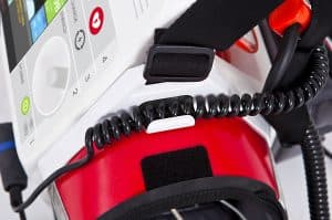 Défibrillateur multiparamétrique Rescue Life 9 : gros plan sur les câbles spiralés, la sangle et les commandes du défibrillateur