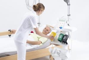 Infirmière installant les brassards MESI mTABLET ABI sur un patient alité