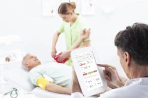 Médecin consultant les résultats ABI sur la tablette MESI pendant l’examen d’un patient