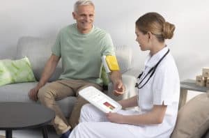 Infirmière tenant la tablette MESI pendant une mesure de tension avec brassard connecté