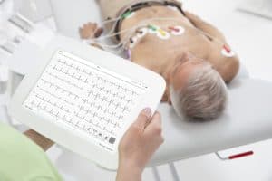 Professionnelle de santé consultant un tracé ECG sur la tablette MESI pendant l’examen