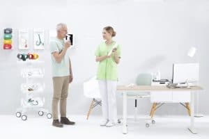 Patient debout utilisant le spiromètre MESI mTABLET SPIRO face à une professionnelle de santé
