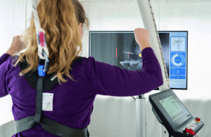Système de rééducation par réalité virtuelle VAST.Rehab : patiente effectuant un exercice des membres supérieurs suivi sur un écran
