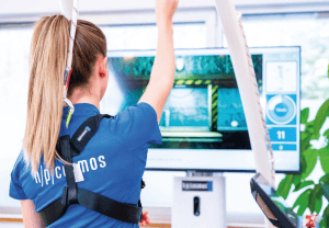 Système de rééducation par réalité virtuelle VAST.Rehab : patiente équipée de capteurs face à un écran d’exercices de rééducation