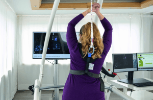 Système de rééducation par réalité virtuelle VAST.Rehab : patiente levant les bras pendant une séance de rééducation virtuelle
