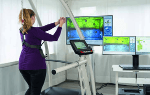 Système de rééducation par réalité virtuelle VAST.Rehab : patiente réalisant un exercice avec retour visuel sur plusieurs écrans de contrôle