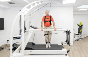 Système d'entraînement à la marche robowalk® : patient debout dans le système robowalk avec harnais de sécurité