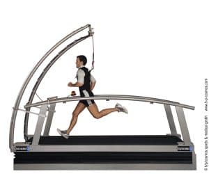 Tapis roulant médical H/P/Cosmos saturn® : coureur en pleine foulée sur le tapis roulant incurvé avec harnais de sécurité