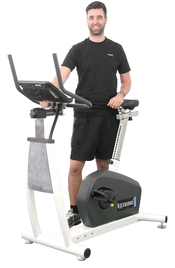 Ergomètre médical torqualizer® med 1200 : utilisateur debout à côté de l’ergomètre avec guidon et console réglables