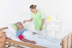 Infirmière mesurant la température frontale d’un patient avec le thermomètre MESI mTABLET