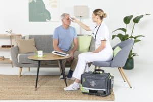 Professionnelle de santé mesurant la température frontale d’un patient à domicile