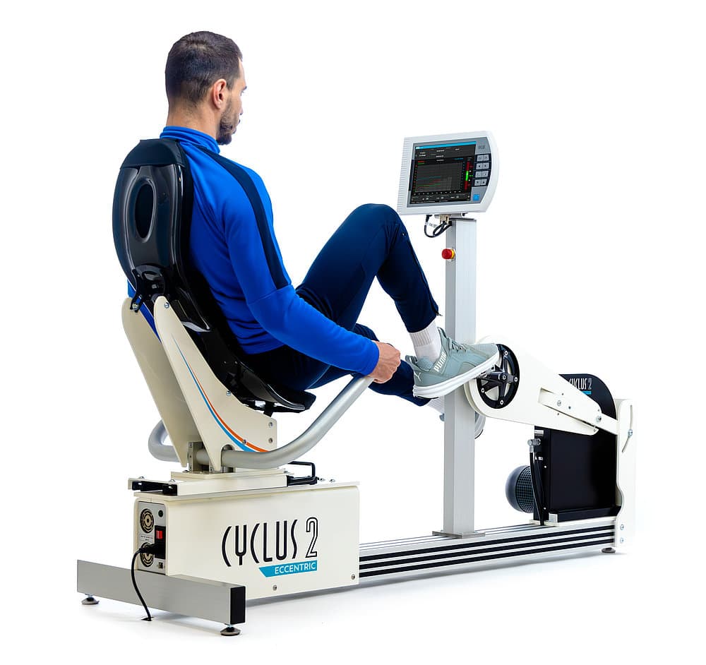Ergomètre semi-allongé excentrique Cyclus 2 Recumbent Eccentric 2WAY : patient pédalant en position semi-allongée avec suivi des données sur la console